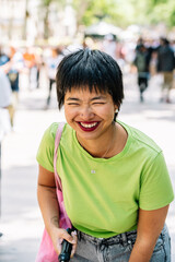Young woman laughing with short hair and green t-shirt in urban setting