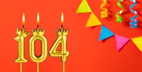 Number 104 birthday candle on an orange background with pennants