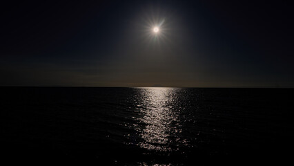Glimmering reflection of bright star on rippling ocean surface at twilight