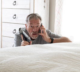 A senior citizen is protecting himself with a handgun from an intruder in his bedroom while calling the police on his cell phone
