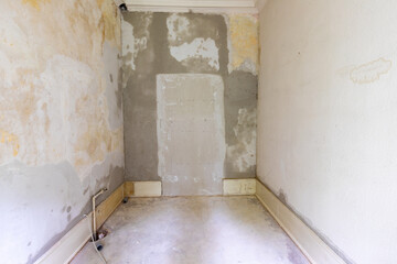 enovated room with plaster wall and wooden panels at the floor before covered by woodchip wallpaper after wall plastering