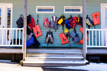 Colorful life vests hanging on a porch in the off-season