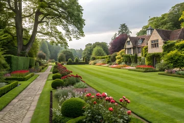 Fototapete English garden with mowed lawn, blooming flowerbeds, leafy trees, and formal landscaping. Peaceful green parkland scene around house during summer in Britain. Vibrant and scenic. © shahjalal