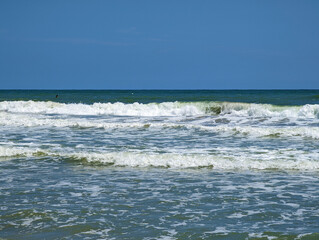 Olas espumosas en playa mediterránea de Mareny de Barraquetes en día soleado de verano en Valencia, España. Agua azul y verde, espuma blanca y agitada, cielo despejado, paradisíaco, naturaleza, costa.