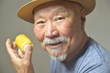 トウモロコシを笑顔で食べる老人