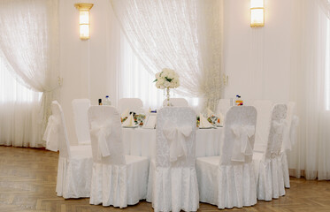 Beautiful wedding table with chairs and table settings in a hall without people.