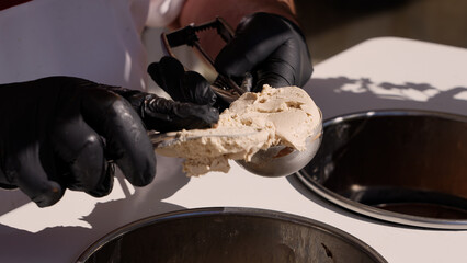 Close up of gloved hands using an ice cream scoop to serve the famous Tartufo dessert in Pizzo, Calabria