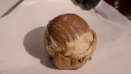 Close up of a tartufo ice cream dessert, a culinary specialty from Pizzo, Italy, being prepared on white parchment paper