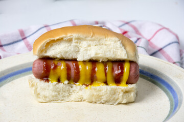 Hot dog with ketchup on a white plate. Close up.