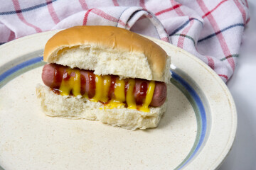 Hot dog with ketchup on a white plate. Close up.