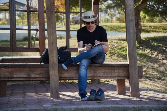 Man writing journal notes sitting on bench