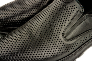 close-up details of black leather classic summer shoes with perforated trim.