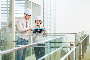 タブレットPCを見ながらビルの室内を点検する男女エンジニア