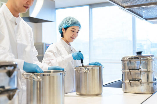 女性、厨房、キッチン、調理、料理、工場、シェフ、調理師、給食センター、給食室、日本人、学校、笑顔、飲食店、食堂、白衣、衛生、ヘアネット、手袋、大鍋、カレー、スープ、献立、宅食、デリバリー、弁当、ミドルエイジ、給食のおばさん、チームワーク、調理器具、バックヤード、大量、フード、管理、レシピ、メニュー、仕事、アルバイト、パート、店舗、食材、食品、開発、栄養士、働く、食物、清潔感、レストラン、調理室、人