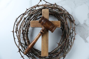 Judge's gavel, wooden cross and crown of thorns on white marble table, top view