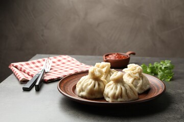Delicious khinkali served with sauce on grey table