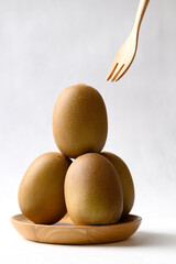 Fresh kiwi fruit with wooden plate and fork on white background, Healthy eating