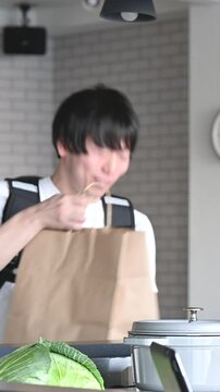 ウーバーの荷物を店員さんから受け取る配達員の男性の縦動画