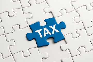 Fototapeta premium White jigsaw puzzle with a blue piece spelling the word TAX