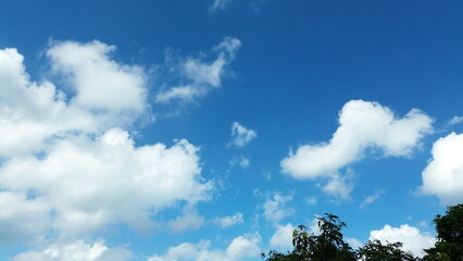 Sun shining through the puffy clouds. Sky view. Beautiful sunny sky. Background with clouds on blue...