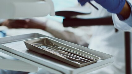 An African American dentist prepares for a dental appointment in a clinic. Dental tools are neatly arranged on a tray, highlighting the professional healthcare environment focused on patient care.