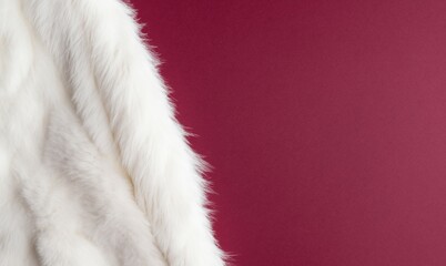 White faux fur texture draped over a burgundy background. A luxurious and trendy material perfect for fashion design, textile backgrounds, and cozy themed compositions. Card or banner. Copy space.