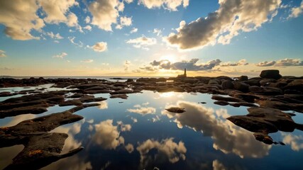 Reflections of clouds on water-covered rocks along the coast at dusk with sunburst - Powered by Adobe
