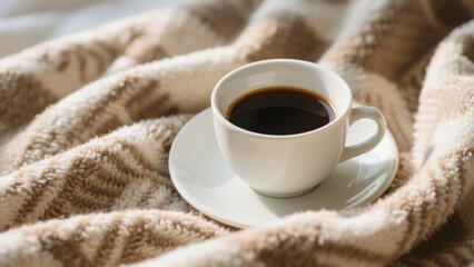 Warm Embrace: A cup of coffee sits nestled amidst a cozy, textured blanket, bathed in the warm glow of morning light, evoking feelings of comfort and peace.