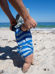 Baby learning to walk on a sunny sandy beach