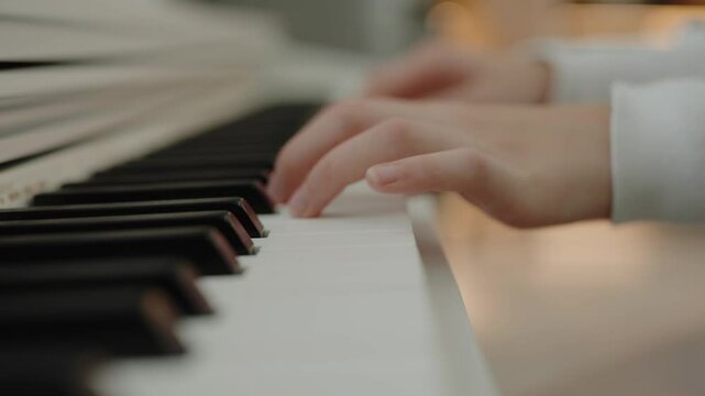 Focused young cute girl having fun playing electric piano. Musician teen student teaching music lesson. A quiet person practices the piano while sitting in his apartment. Hands pressing the piano keys