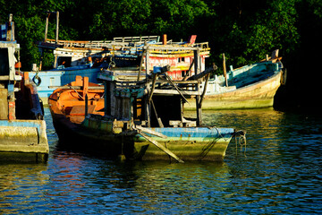 Obraz premium Rustic Fishing Boats Moored in Calm Waters Surrounded by Nature