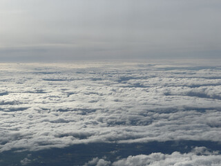 Obraz premium Aerial view of a vast expanse of clouds under a gray sky. The scene captures the soft, fluffy texture of the clouds, creating a serene atmosphere.
