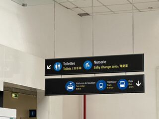 Signage in a public space indicating facilities such as toilets, baby change area, and transportation options like taxis and buses.