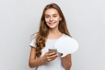 Naklejka premium Woman smiles holding phone and white speech bubble against a plain background