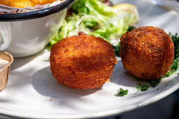Lunch in cafe with vegetarian cheese and green asparagus croquettes served with fresh salad and french fries potato in Bruges, Belgium