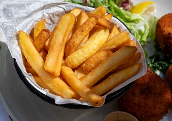 Lunch in cafe with vegetarian cheese and green asparagus croquettes served with fresh salad and french fries potato in Bruges, Belgium