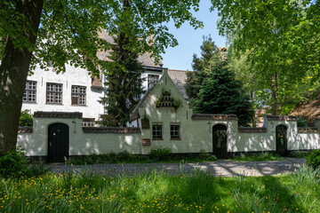 Medieval convent for nuns who weave lace in Bruges, Flanders, small white houses and a park inside the monastery walls, Belgium