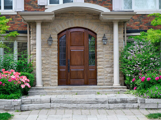 Elegant wood grain front door surrounded by flowers