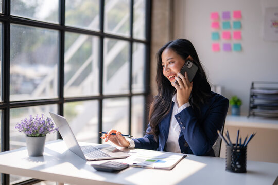 A woman is talking on her cell phone while sitting at a desk