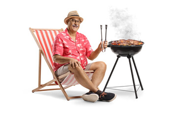 Man sitting in a deck chair and grilling meat on a bbq
