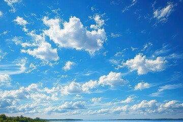 Expansive blue sky filled with scattered fluffy white clouds over a distant flat landscape with green vegetation under bright daylight
