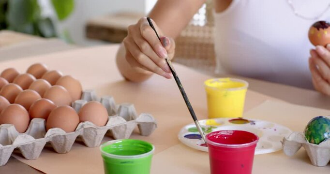 Mother and daughter painting Easter eggs, bonding and smiling together, at garden