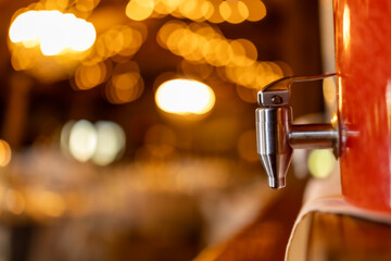 a beverage container holding a pink liquid with a silver spout in front of a bokeh background at a wedding