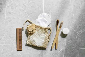 Sustainable self-care items top view, bamboo toothbrushes, comb, toothpaste in white tube, reusable pads on grey marble. Sustainability and minimalism, Natural organic bathroom products
