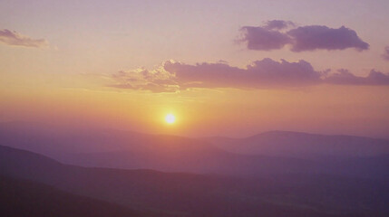 Fototapeta premium Golden sunset over a serene landscape, warm light through clouds, orange and purple hues blending in harmony