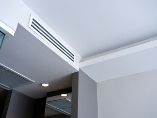 From bottom view of air conditioning wall mounted ventilation system on ceiling in white clean hotel guest room background. Hotel room air ventilation grill on the wall.