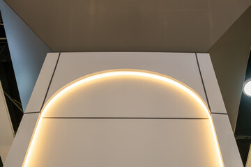Architectural detail of a curved arch with integrated warm LED strip lighting. Modern interior design with minimalist lines and ceiling contrast. Abstract wall feature with soft illumination.