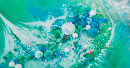 Drop emulsion. Oil paint bubble. Colorful acrylic ball flow in green liquid. Art wave fizz blue particles mix abstract defocused background.
