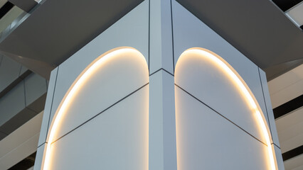 Modern architectural corner with curved LED lighting on smooth gray panels, captured from low angle in a contemporary indoor space.