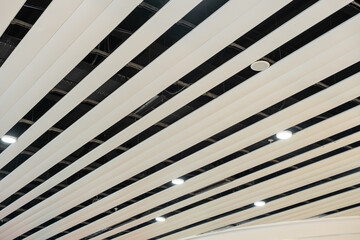 Modern slatted ceiling with integrated LED downlights and clean architectural lines, creating a minimalist and futuristic interior design for commercial or public spaces.